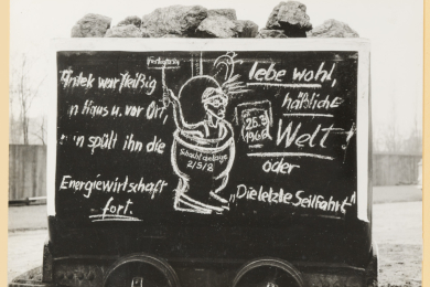 Karikatur auf einem Förderwagen mit einem aus einem Klosett schauenden Bergmann. 