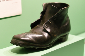 Schwarzer Lederstiefel auf hellgrünem Sockel