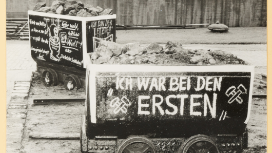 Zwei mit Protest-Zeichnungen versehene Förderwagen in einem Betriebshof. 