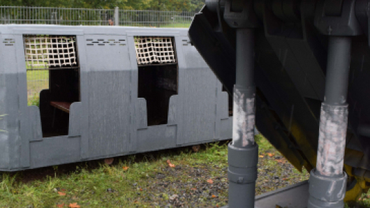 Der Waggon einer Grubenbahn steht hinter einem Ausbauschild